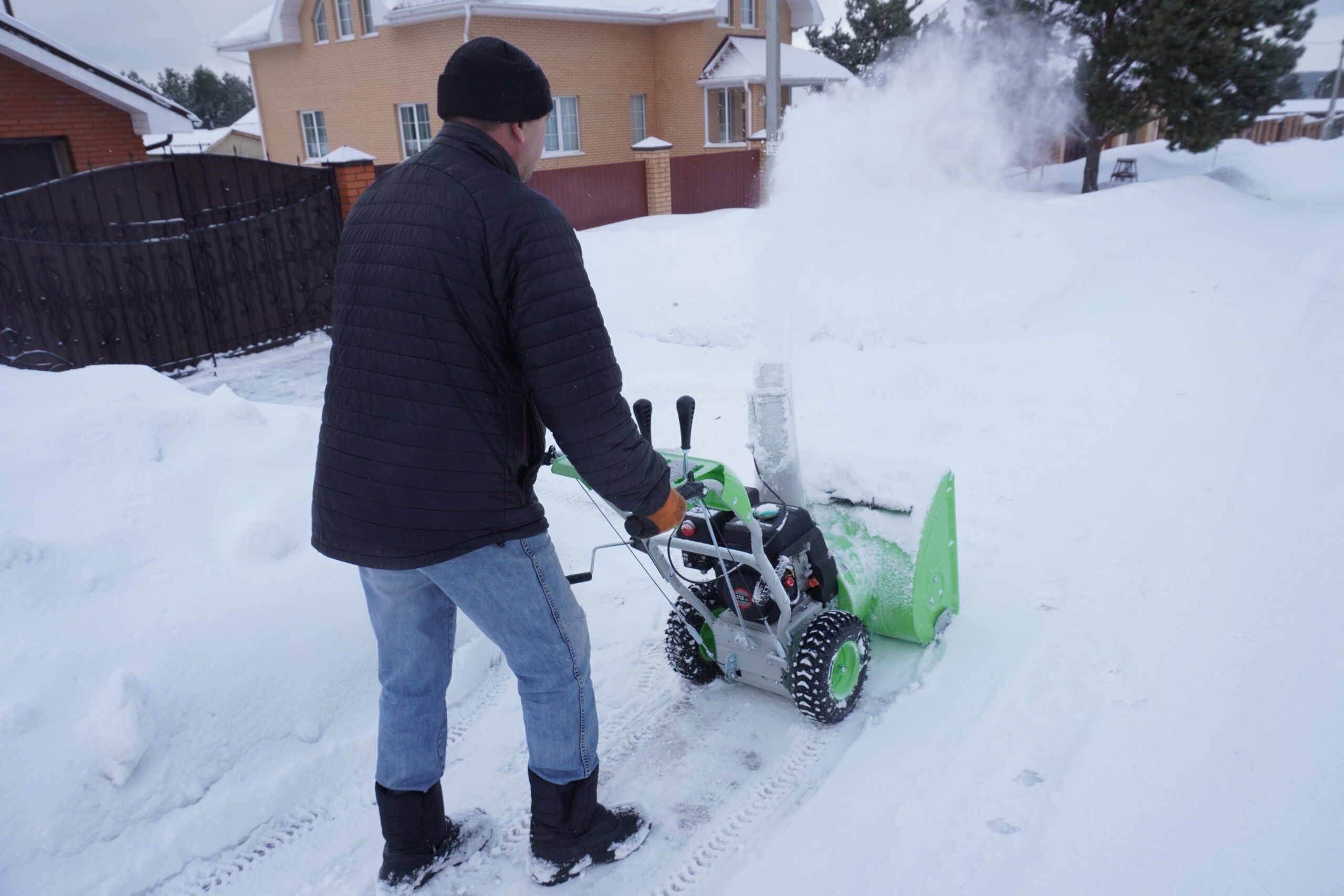 A man cleans snow in the winter in the courtyard of the house,